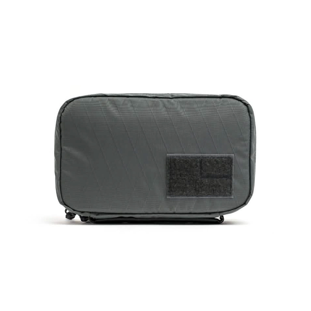 The GR1 Field Pocket USA - X-PAC is a rectangular gray pouch with a black front patch, ideal as a travel accessory and shown against a white background.