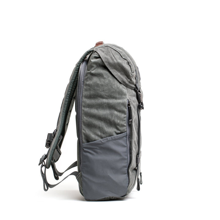The gray GORUCK M24 waxed canvas rucksack features side pockets and extra padded shoulder straps, shown upright on a white background.