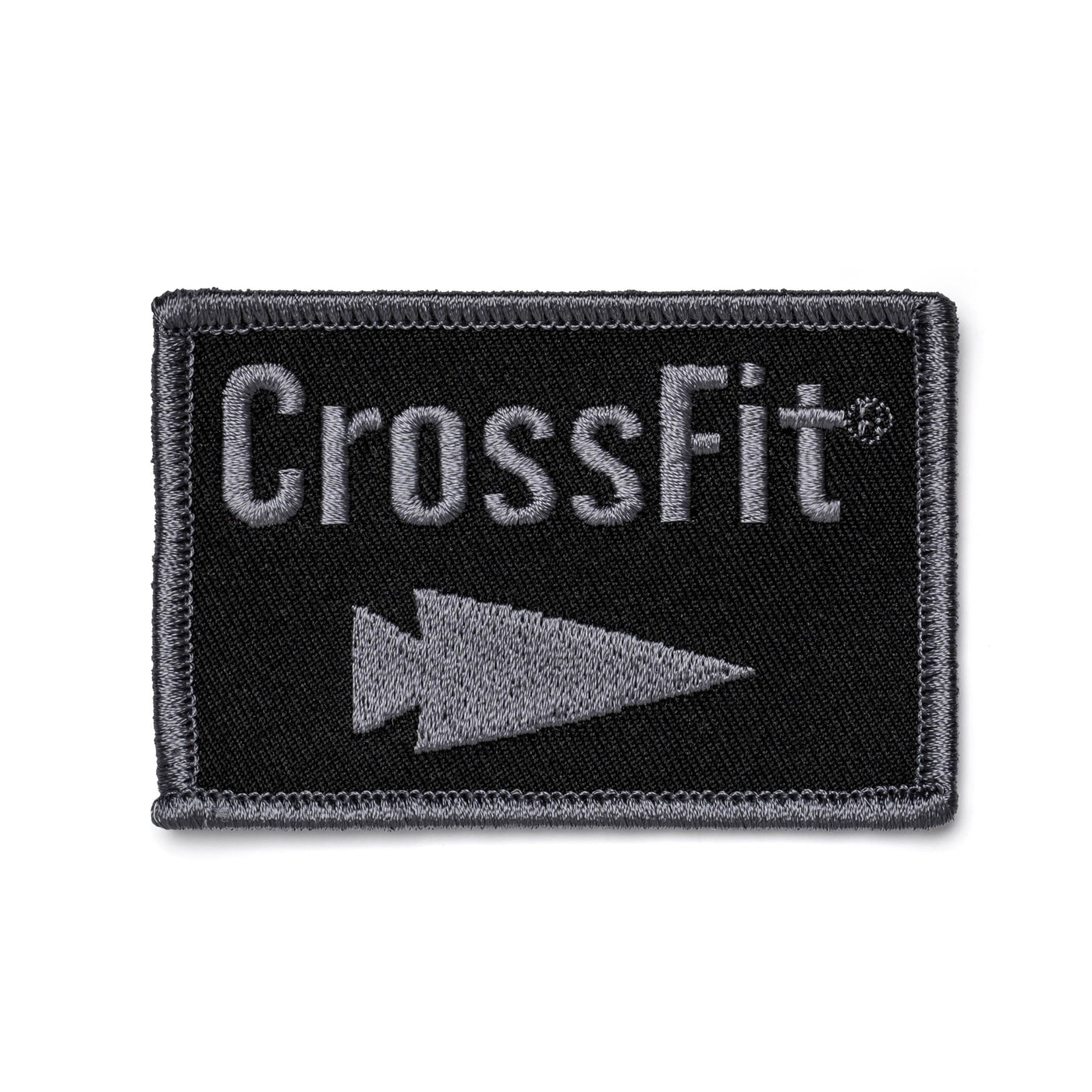 A rectangular black patch bordered in gray features the word CrossFit in bold gray text, with a distinct gray triangle pointing to the right below it, capturing the GORUCK style. This product is known as Patch - GORUCK x CrossFit from GORUCK-DEMO.