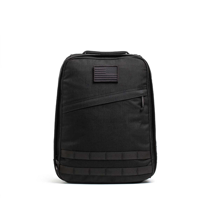 The Radio Ruck USA Throwback backpack features a muted American flag patch, front zipper pocket, horizontal webbing accents, and a bombproof laptop compartment inspired by Special Forces durability.