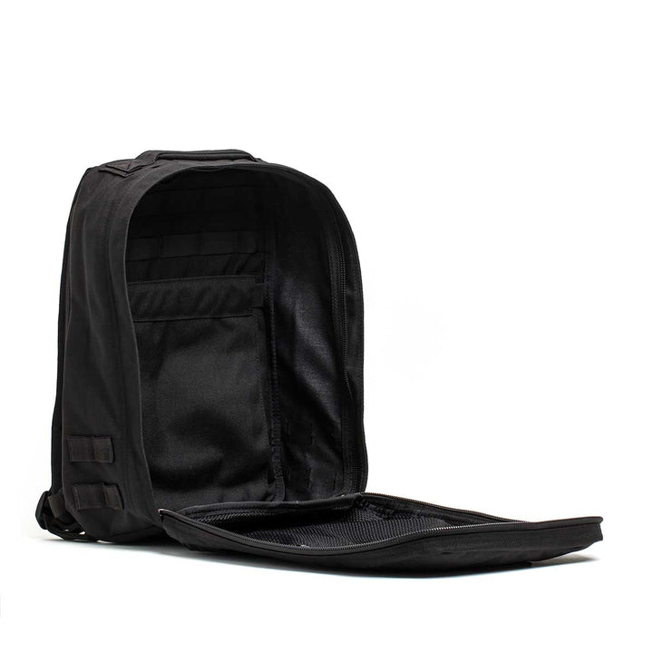 The Radio Ruck USA Throwback backpack, shown with its main compartment open, reveals interior pockets, a zippered mesh section, and a bombproof laptop compartment inspired by Special Forces durability.