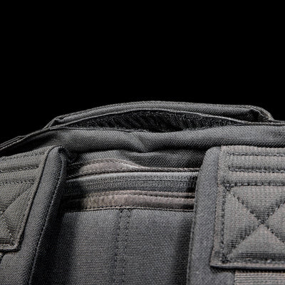 Close-up of the Radio Ruck USA Throwback, a black tactical-inspired backpack with visible stitching and padded shoulder straps, designed for durability and versatility, set against a black background.