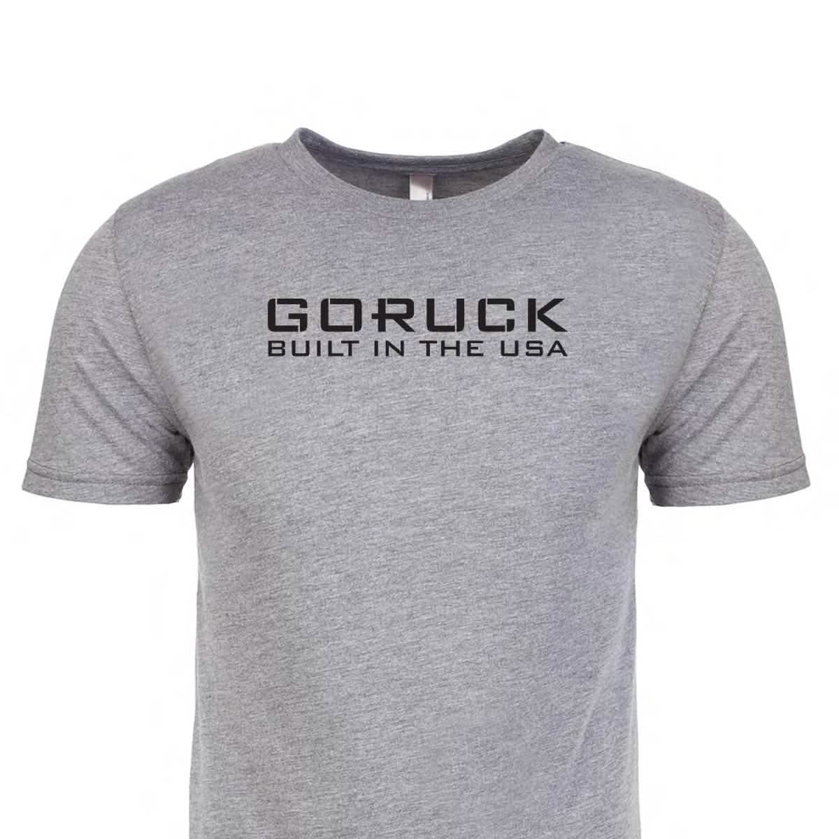 The Reverse Flag Tee - Tri-Blend by vendor-unknown is a gray T-shirt with black text on the front that reads "GORUCK BUILT IN THE USA," symbolizing courage and respect with a nod to military uniforms.