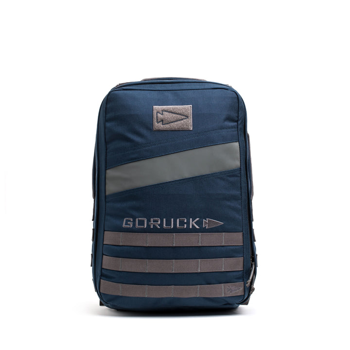 The navy blue Rucker 4.0 backpack with gray accents and logo features a dedicated Ruck Plate compartment, shown standing upright on a white background.