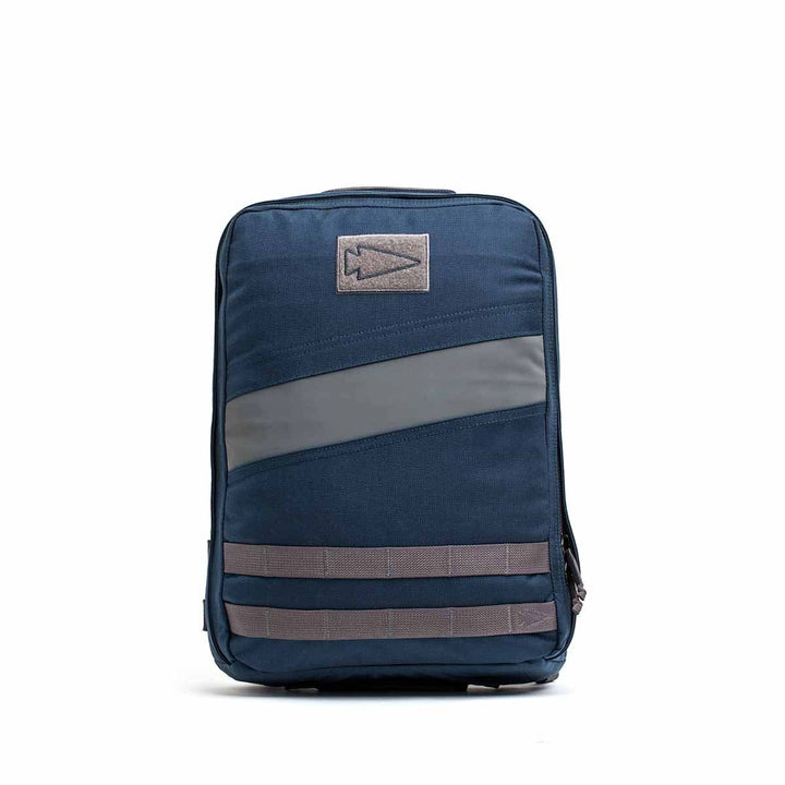 A Rucker 4.0 rucksack in navy blue with gray diagonal stripes and patch details is displayed against a white background.