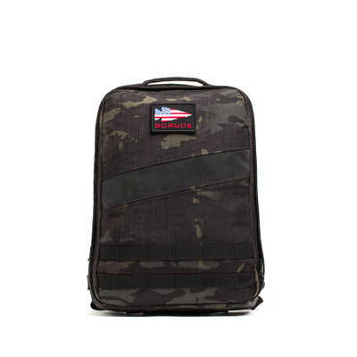 The Rucker 4.0 is a black camo rucksack featuring a top handle and an American flag patch labeled "GORUCK"—ideal for rucking or hauling your Ruck Plates.