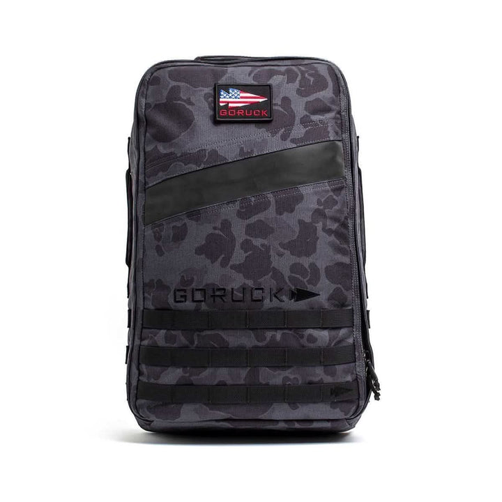 The Rucker 4.0 is a gray camouflage backpack with black accents, an American flag patch, and "GORUCK" logo on the front—built for rucking and securely holds your Ruck Plates.