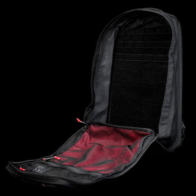 The GR1 Shooter 26L - Built by SCARS backpack is fully unzipped, showing a red mesh interior pocket and organized compartments—rugged enough for any adventure, just like every Shooter Ruck tested by the SCARS team.