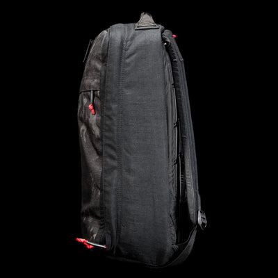 Side view of a black GR1 Shooter 26L - Built by Scars backpack in rugged CORDURA® fabric, with red zipper pulls, shown against a plain black background.