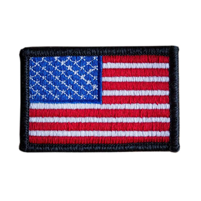 The "Patch - American Flag" by vendor-unknown is an embroidered patch showcasing the United States flag design. It features red and white stripes with a blue rectangle in the top left corner adorned with white stars, all bordered in black, and comes with a VELCRO® backing for effortless attachment.
