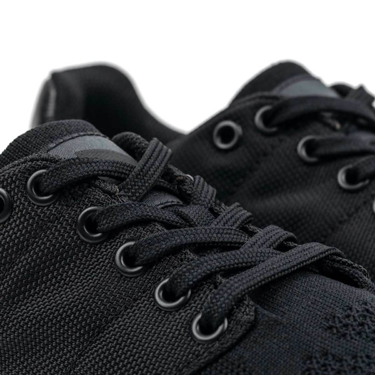 Close-up of the Men's Ballistic Trainers - Blackout w/ Black Reflective Spearhead by GORUCK, showcasing a pair of black athletic shoes made with CORDURA® Ballistic Nylon. These shoes feature textured fabric and black laces with metal eyelets, designed for functional fitness footwear. They offer a sleek, modern look complemented by durable 3X Support™ for enhanced performance.