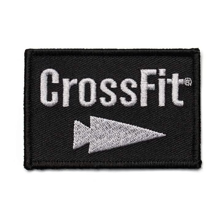 The Patch - GORUCK x CrossFit by GORUCK-DEMO showcases a finely embroidered CrossFit logo with sharp white lettering and an arrow icon set against a stylish black backdrop, ideal for enhancing your GORUCK equipment.