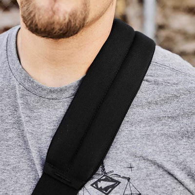 Close-up of a person wearing a grey t-shirt with a graphic design, complemented by the rugged look of GORUCK's Kit Bag (Includes Shoulder Strap) hanging from a black strap. Only the lower part of the face is visible, highlighting a neatly trimmed beard.