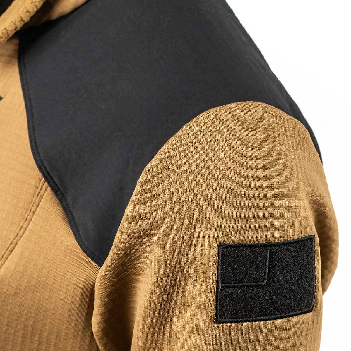 Close-up of a brown Men’s Half Zip - Polartec Grid Fleece by GORUCK, featuring a black shoulder panel and a rectangular Velcro patch on the sleeve. Crafted with ToughDry Fabric, its detailed weave pattern is visible, highlighting the jacket's durability and style.