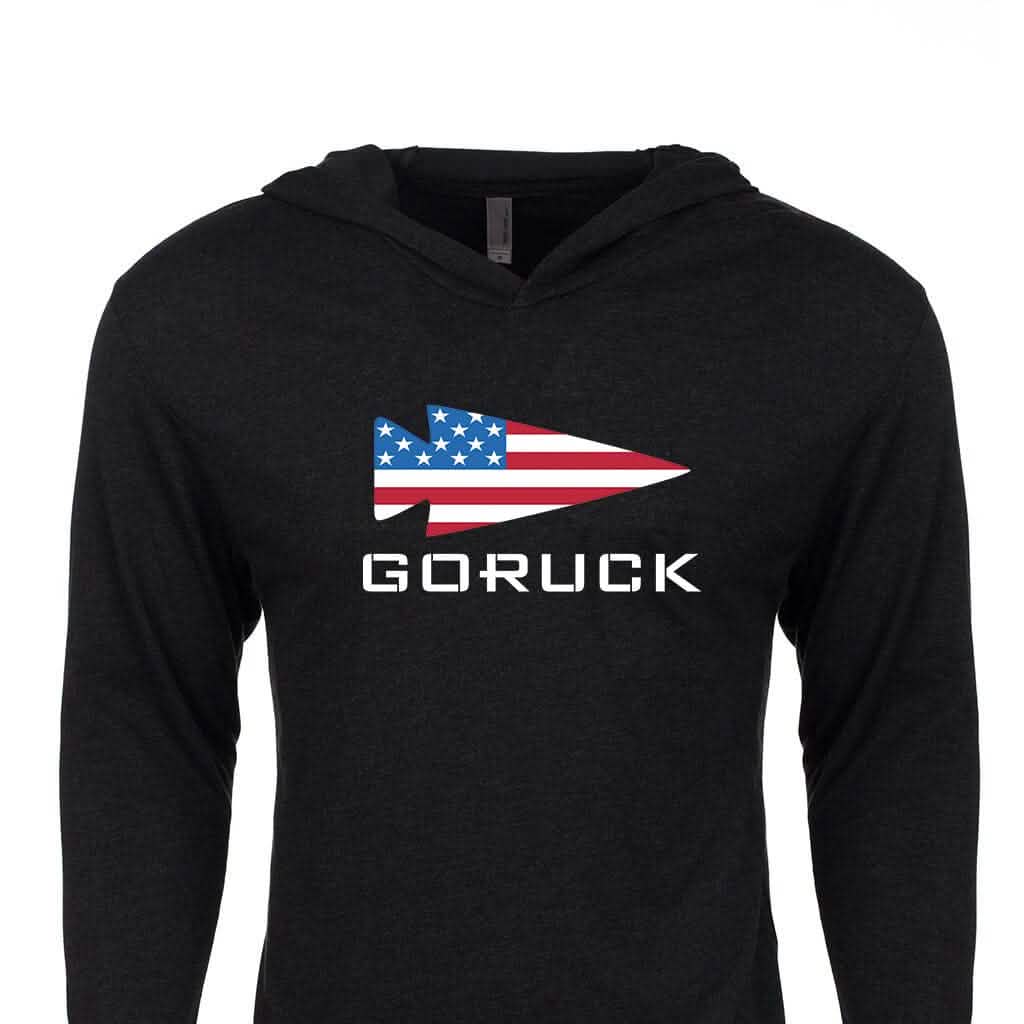 The GORUCK USA Hoodie - Tri-Blend by GORUCK is a black hoodie that features the iconic GORUCK logo, with a stylized spearhead adorned with an American flag design and the word "GORUCK" boldly printed in white underneath, embodying Special Forces heritage inspiration.