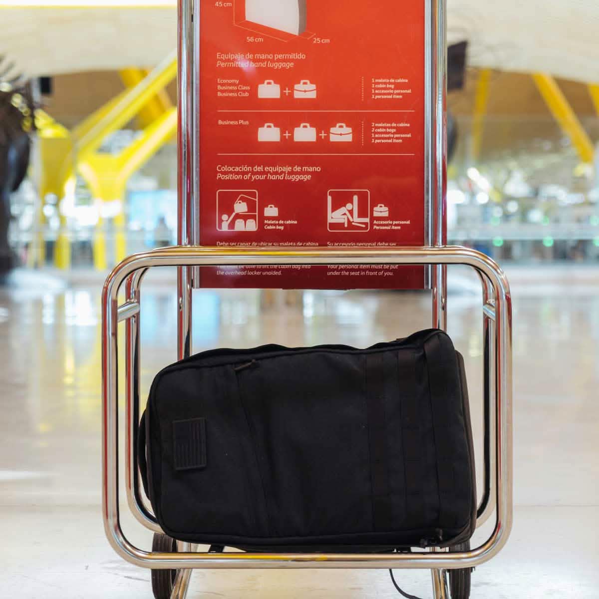 A GR1 USA - Cordura (The Original Ruck) black bag from GORUCK, crafted with the precision of American manufacturing, sits in a luggage sizer at the airport, seamlessly verifying its compliance with hand luggage size restrictions.