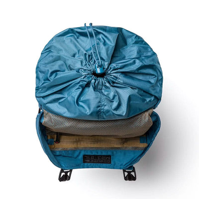 Introducing the GORUCK M23, a contemporary rucksack in Seaspray and Speed Tan, crafted from robust Ripstop ROBIC® material. It boasts an open top with a mesh pocket and drawstring closure, making it ideal for outdoor adventures. Inside, you'll find a label marked "Border Magnetik," ensuring easy organization while on the move.
