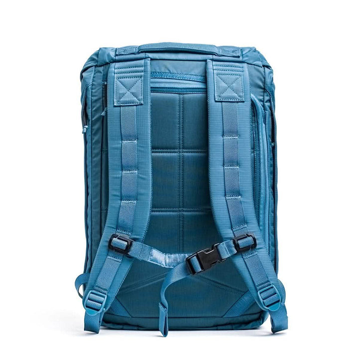 The M23 - Ripstop ROBIC® by GORUCK in Seaspray + Speed Tan is a contemporary rucksack with a vibrant blue hue. It comes equipped with padded adjustable shoulder straps, a chest buckle, and a rectangular cushioned back panel. Constructed from durable materials, its design features visible stitching and seams to ensure enhanced strength.