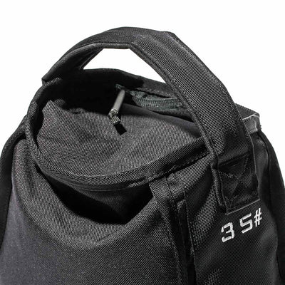 Close-up of a black fabric bag with a partially open zipper, exposing the interior. The bag, echoing an endurance design, features sturdy handles and a stitched label displaying "GORUCK". The material looks durable and textured.