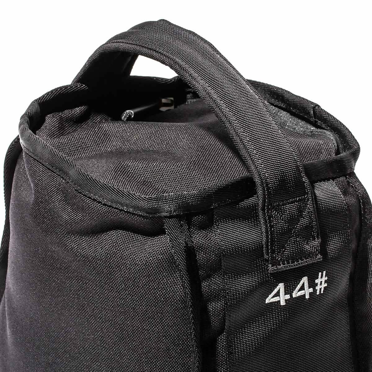 A close-up of a textured black Sand Kettlebell by GORUCK reveals reinforced handles and the number 4.4# printed in white on its side, highlighting its endurance design ideal for versatile workouts on the go.