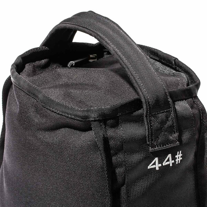 A close-up of a textured black Sand Kettlebell by GORUCK reveals reinforced handles and the number 4.4# printed in white on its side, highlighting its endurance design ideal for versatile workouts on the go.
