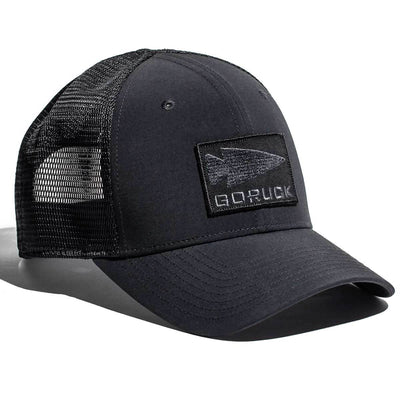 The Performance Trucker Hat - GORUCK Spearhead by GORUCK is a black trucker hat with a mesh back and adjustable Velcro strap, featuring an embroidered patch with an arrow design and the word GORUCK. Made from sweat-wicking material, it combines comfort and style effortlessly.