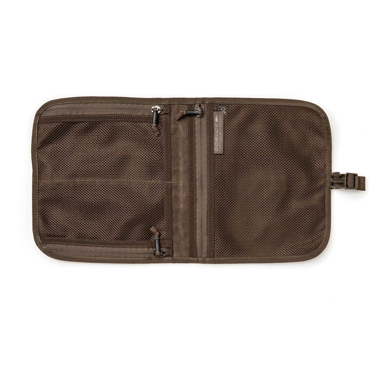 The Wire Dopp - Waxed Canvas by GORUCK is a robust brown travel organizer made from durable waxed canvas, equipped with two primary compartments. One side features a zippered mesh pocket, while the other includes slots for small items. Additionally, it includes a strap with a buckle on the side to keep your travel essentials perfectly organized.